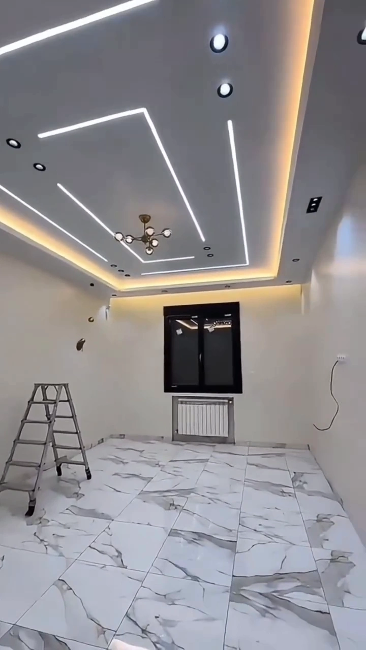 Modern false ceiling with recessed linear LED lighting, warm cove lighting, and decorative chandelier installation in Kampala, Uganda by Dynawatt Engineering
