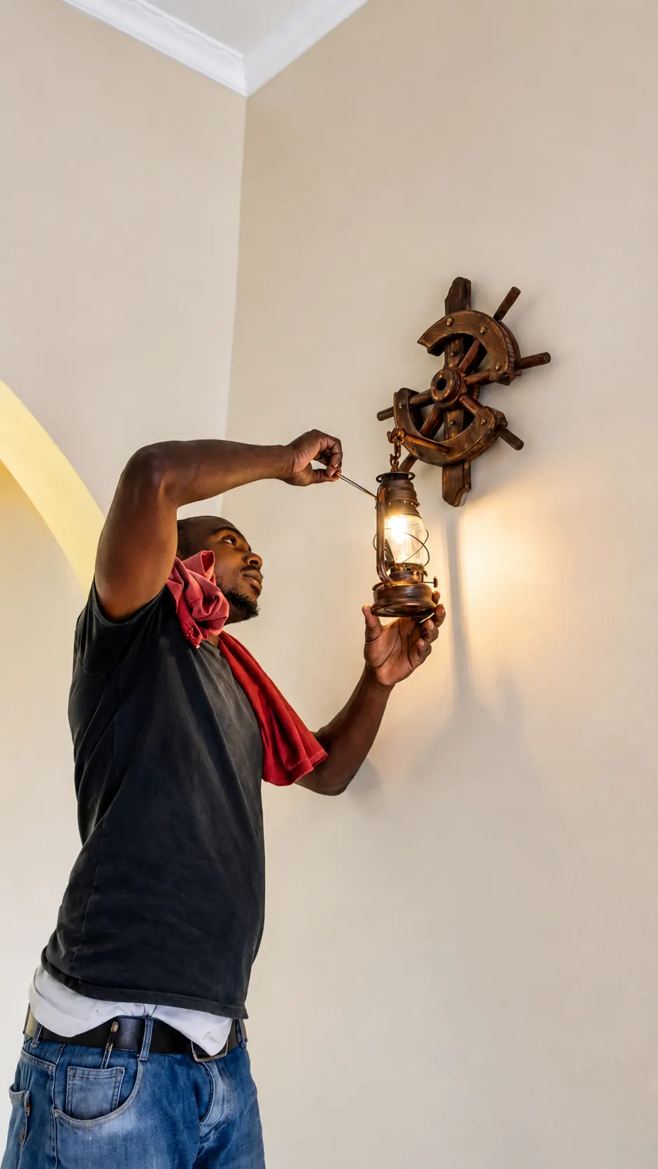 Electrician installing retro ship-wheel themed wall lamp in Hoima